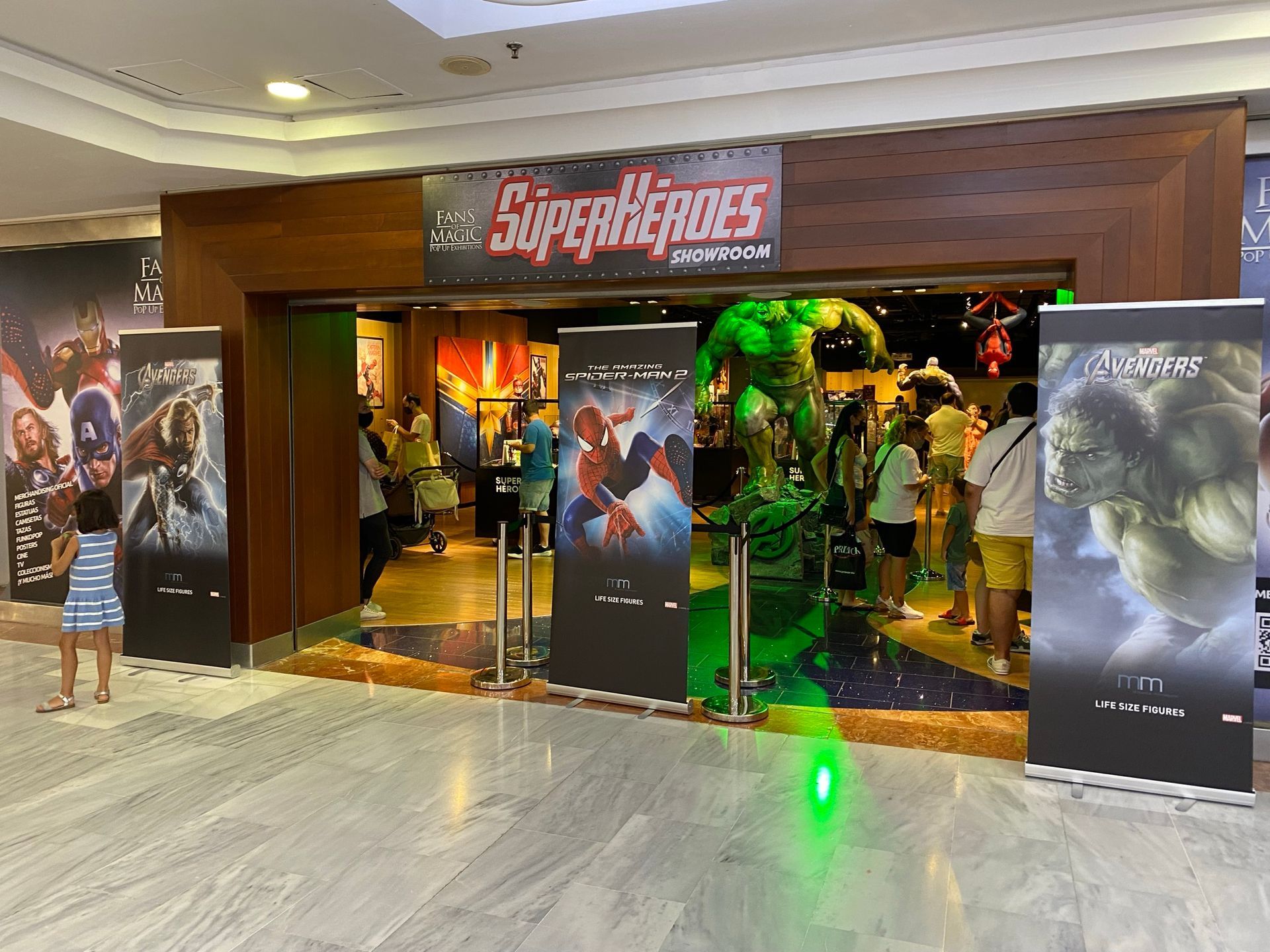 Un grupo de personas está parado afuera de una tienda llamada Superhéroes.