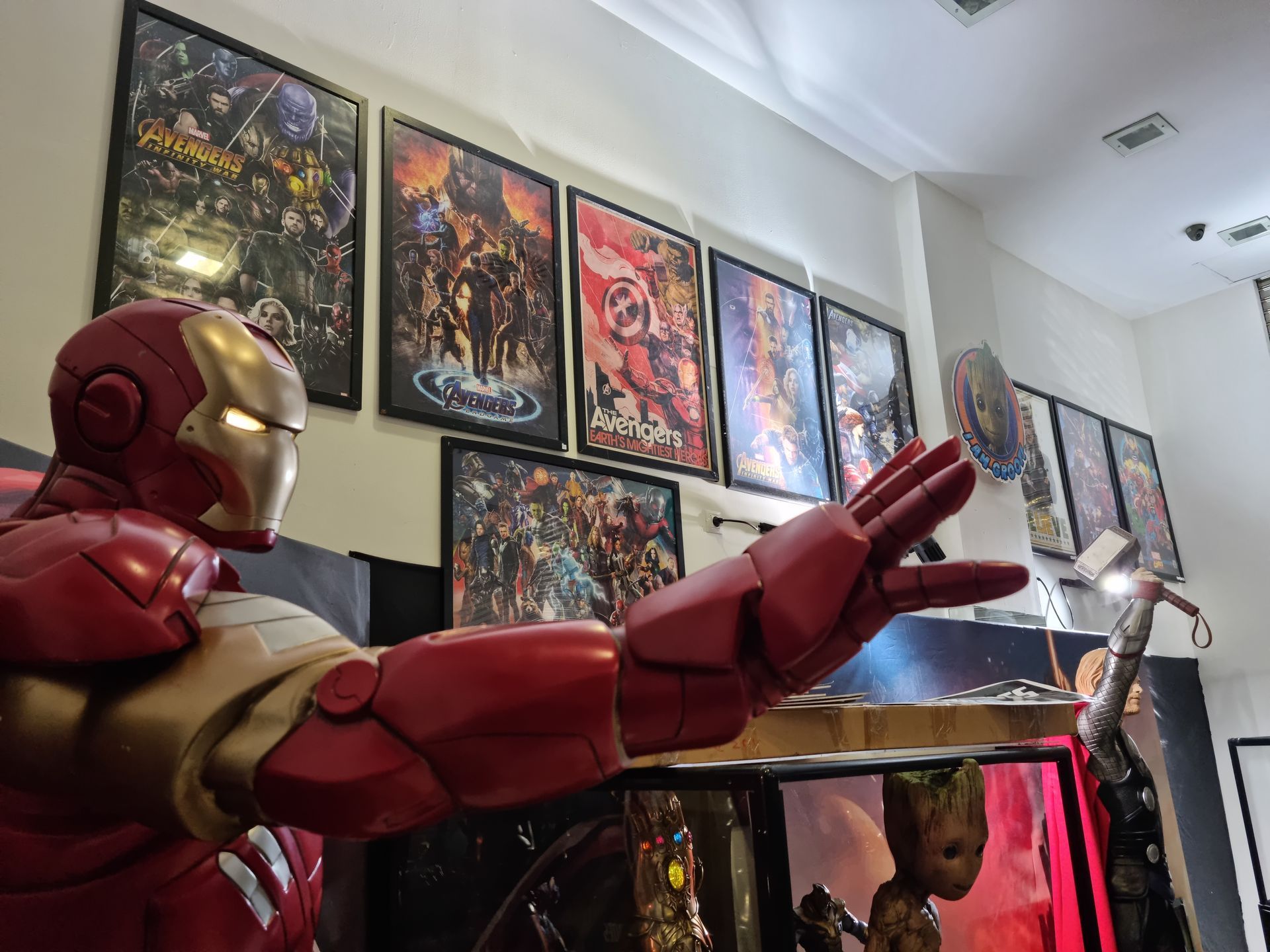 Una estatua de Iron Man está de pie en una habitación con carteles en la pared.
