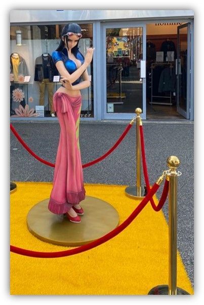 Una estatua de una mujer parada frente a una tienda.