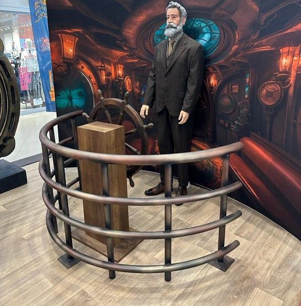 Una estatua de un hombre con barba está de pie junto a un volante.