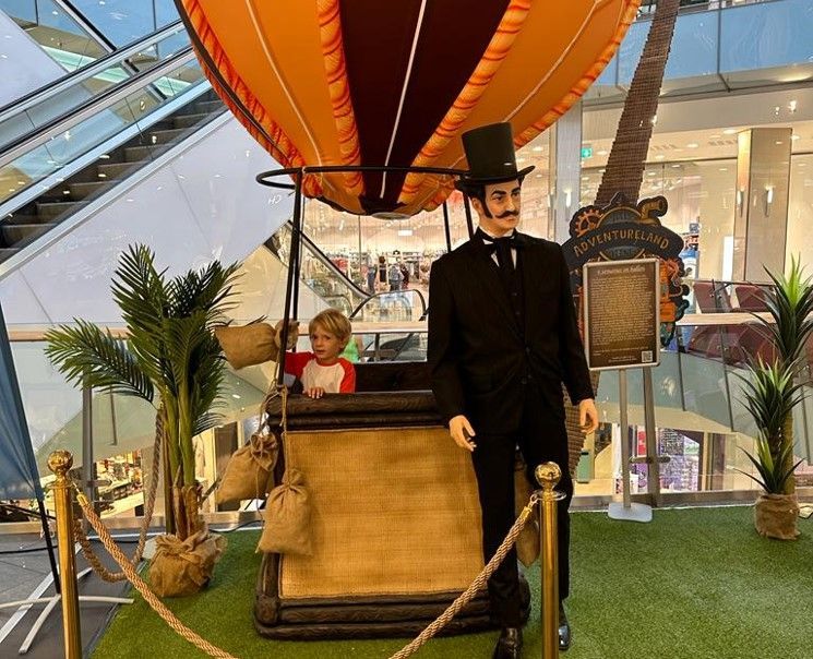 Un hombre con sombrero de copa está de pie junto a un globo aerostático.