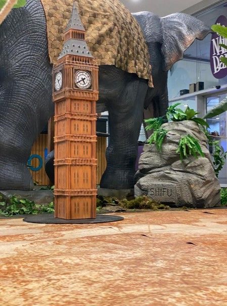 Una estatua de un elefante con una torre de reloj Big Ben frente a ella.
