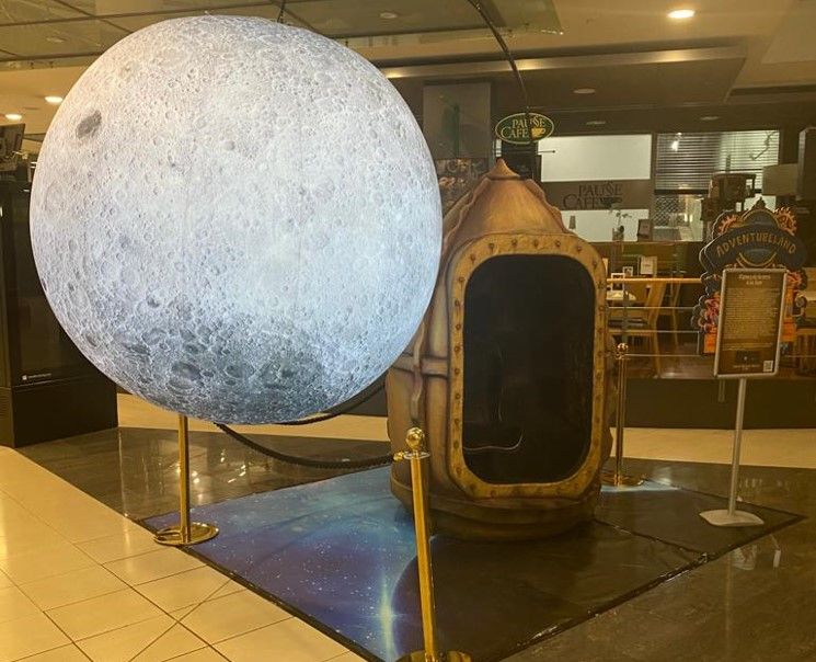 Una gran estatua de la luna está sentada al lado de una estatua más pequeña de la luna.