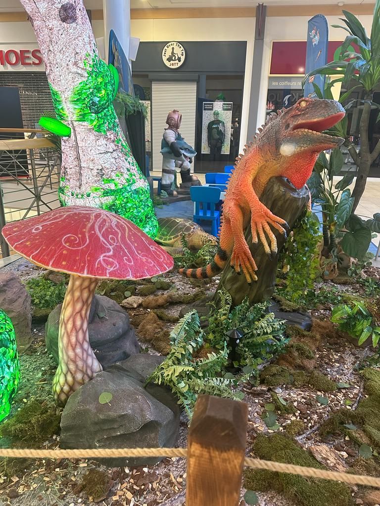 Un lagarto está sentado en una roca al lado de un hongo en un centro comercial.