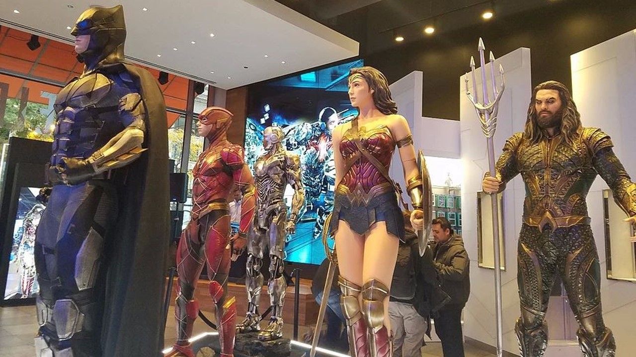 Un grupo de estatuas de superhéroes parados uno al lado del otro en una habitación.