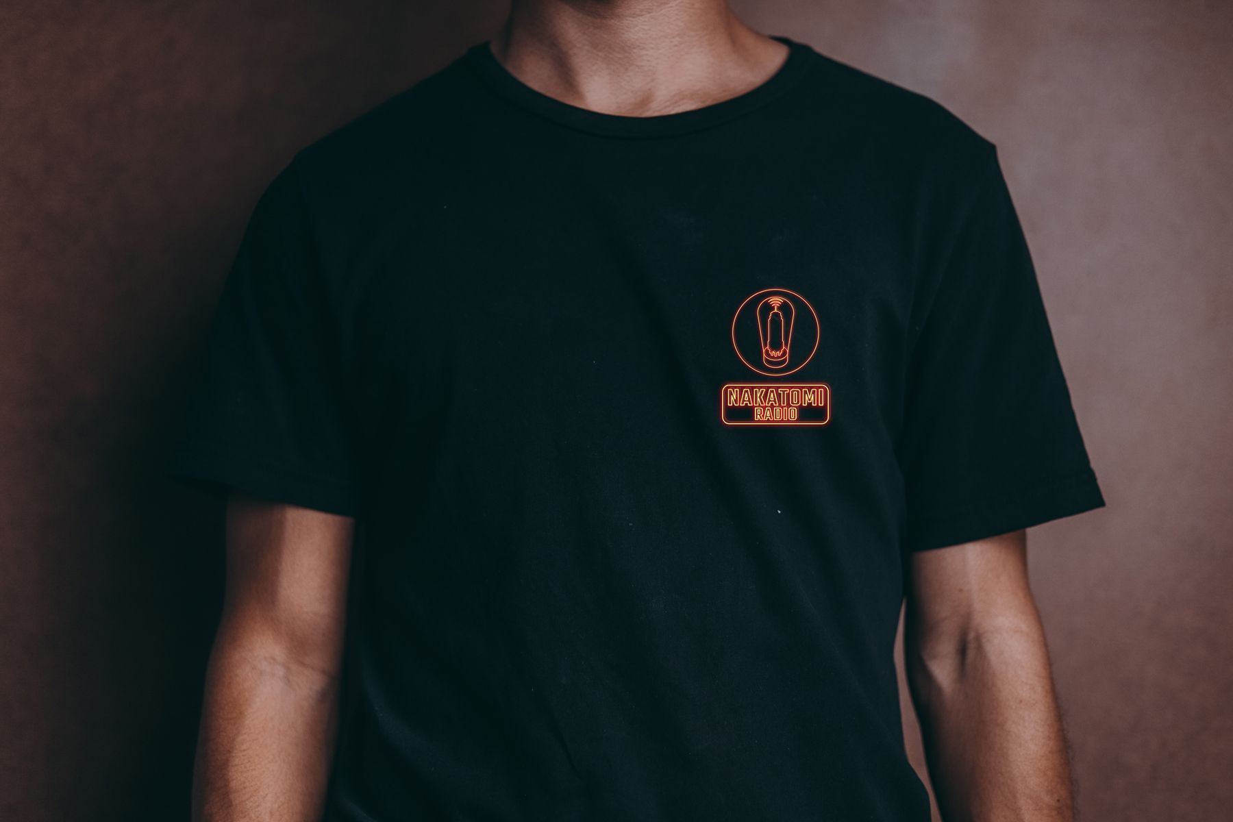 Un hombre lleva una camiseta negra con un logo naranja en la espalda.