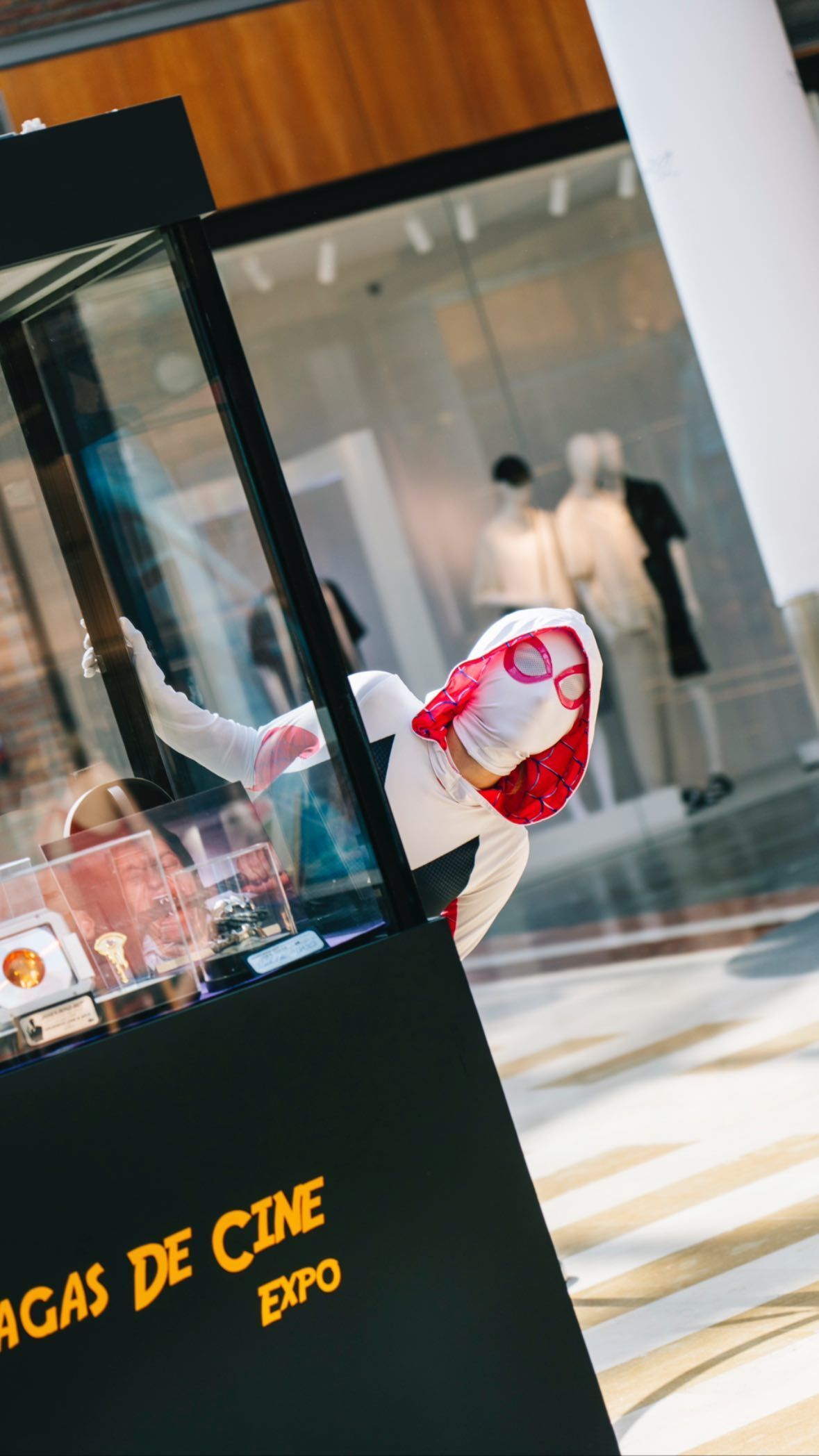 Una persona disfrazada de Spider-Man está parada frente a una vitrina de vidrio.