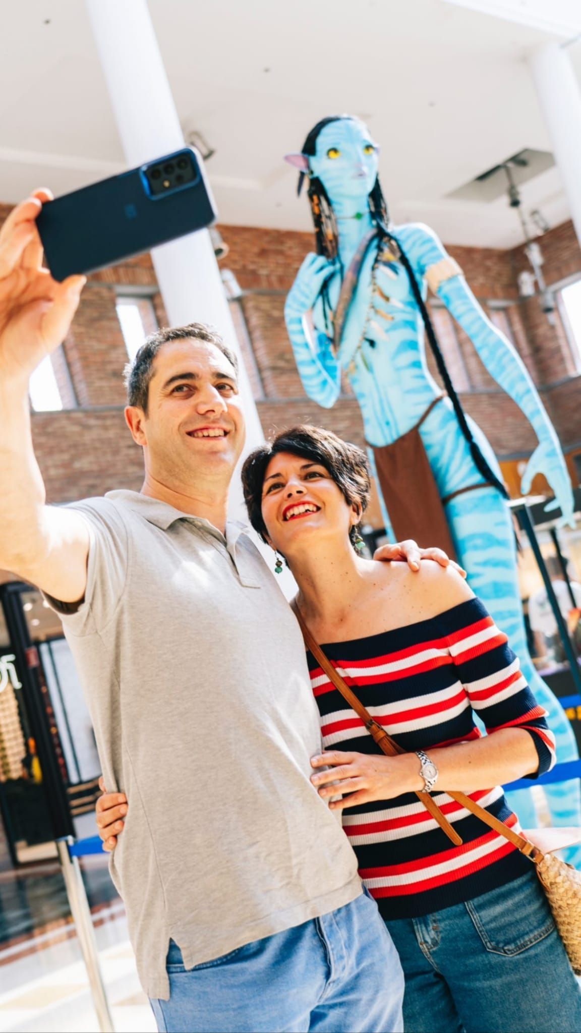 Un hombre y una mujer se toman un selfie frente a una estatua de Avatar.