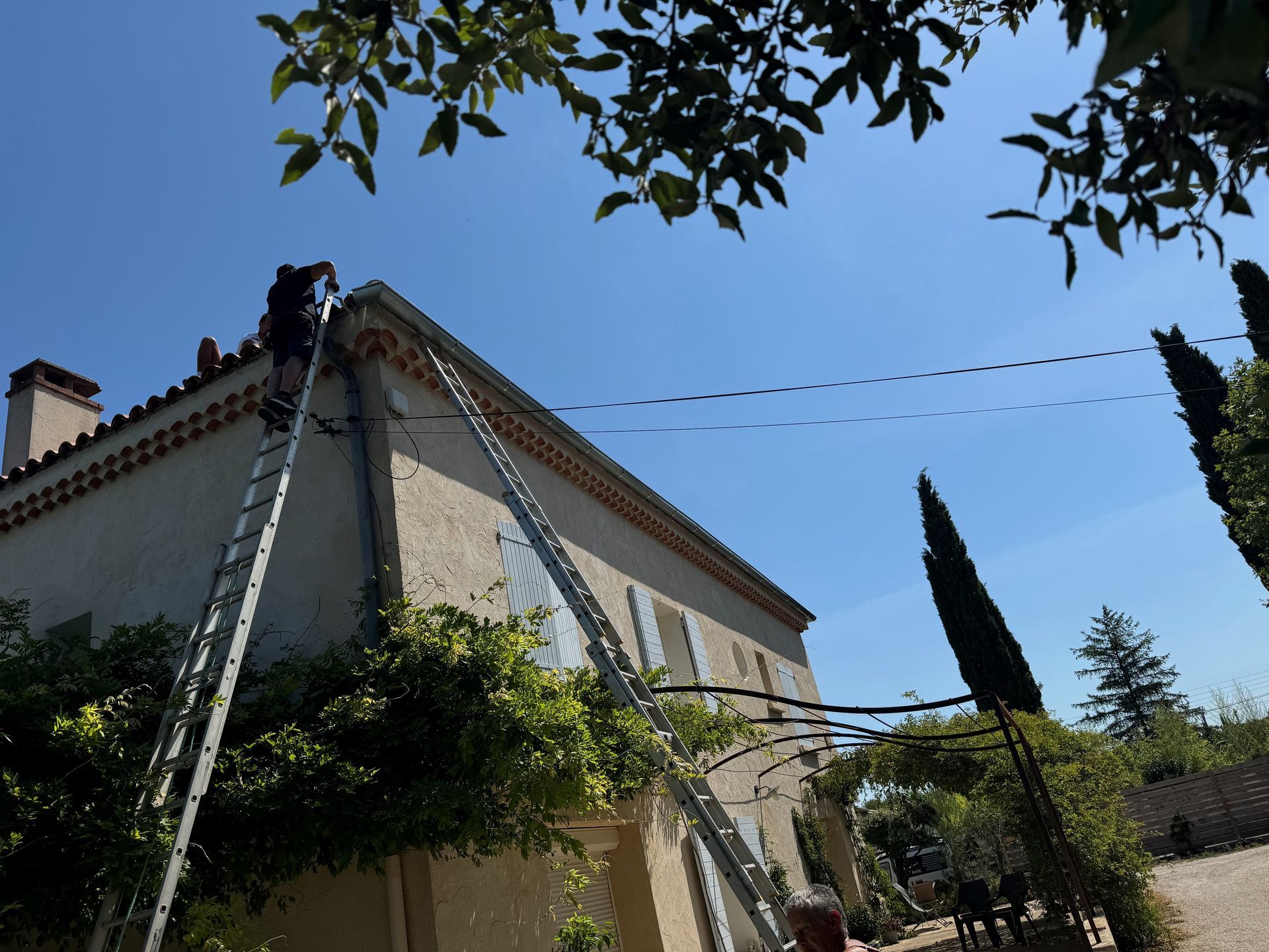 Artisan en haut d'une échelle pour nettoyer le toit