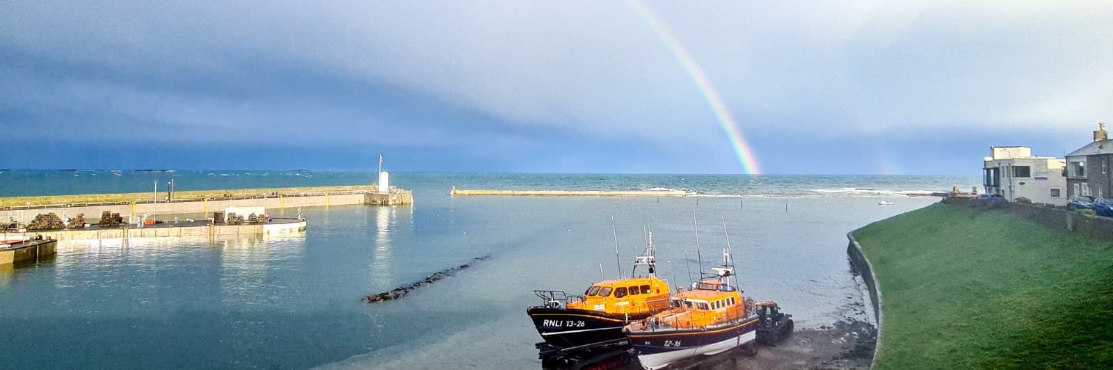 Old and new Seahouses lifeboats side by side in the harbour, photographed from Tidal Cottage