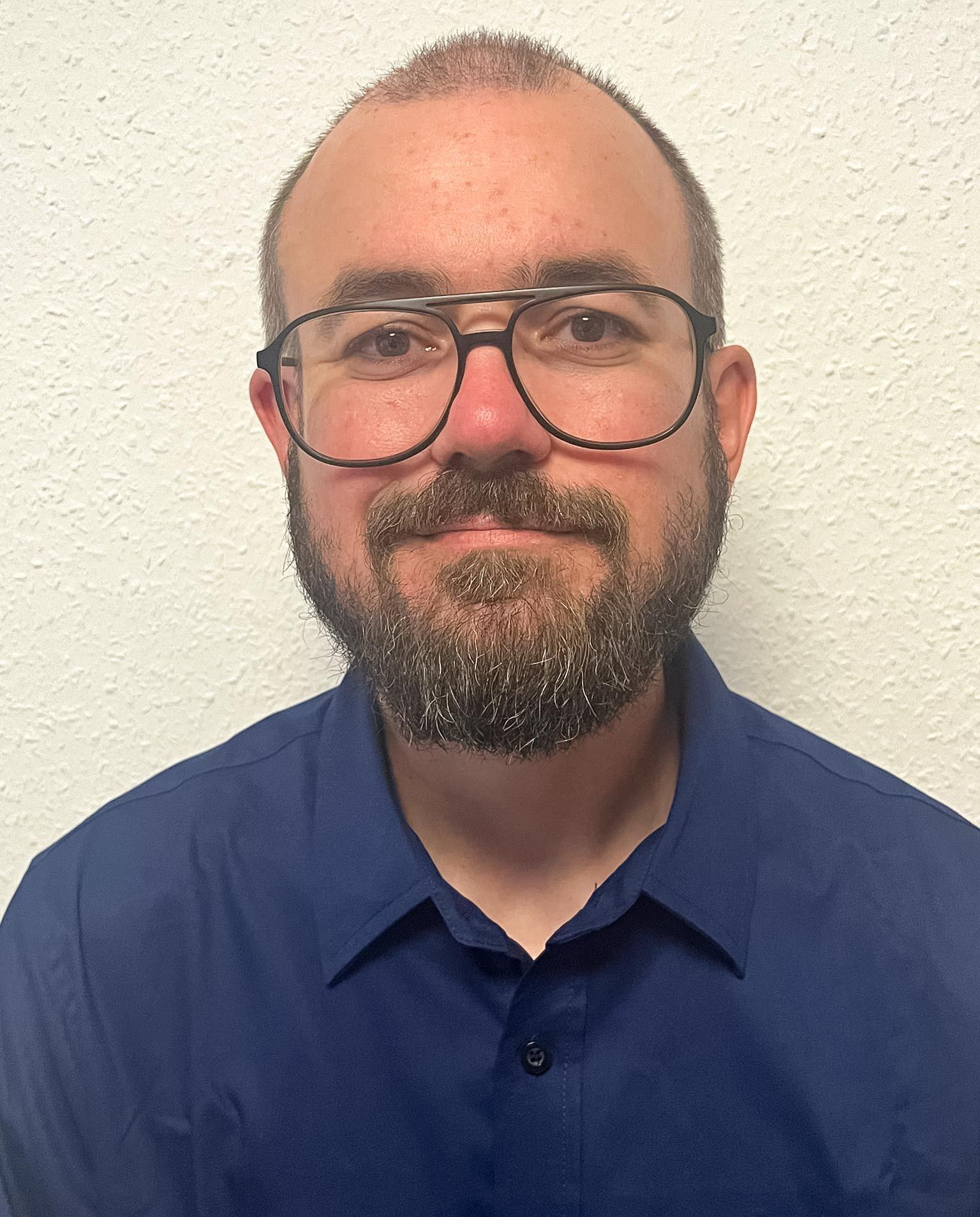 Ein Mann mit Bart, Brille und blauem Hemd