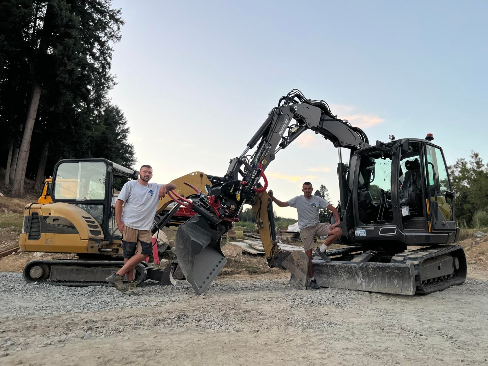 Deux hommes se tiennent entre des excavatrices et un grand bras articulé sur un chantier de gravier.