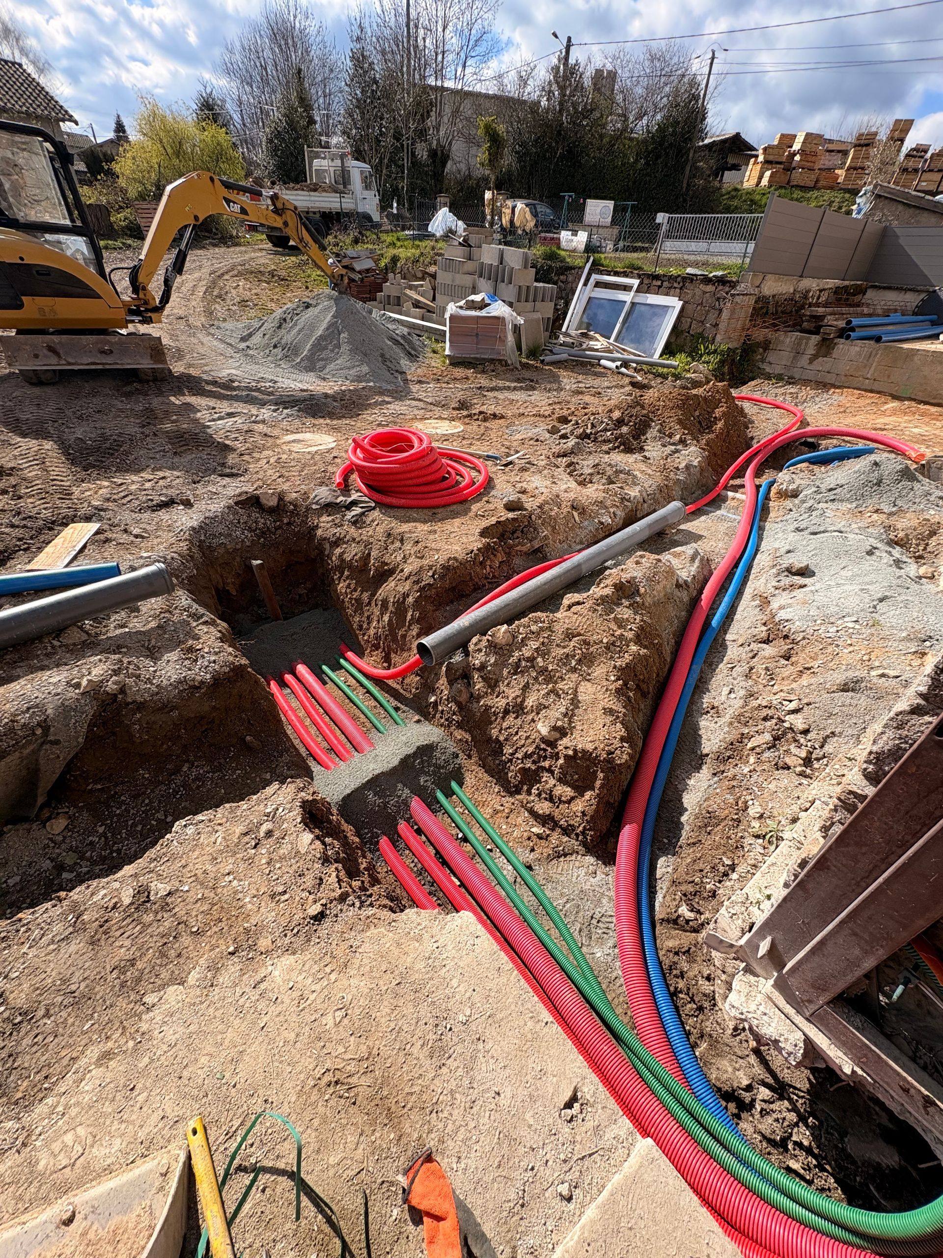Une minipelle charge des gravats dans un camion-benne rouge sur un chantier de construction