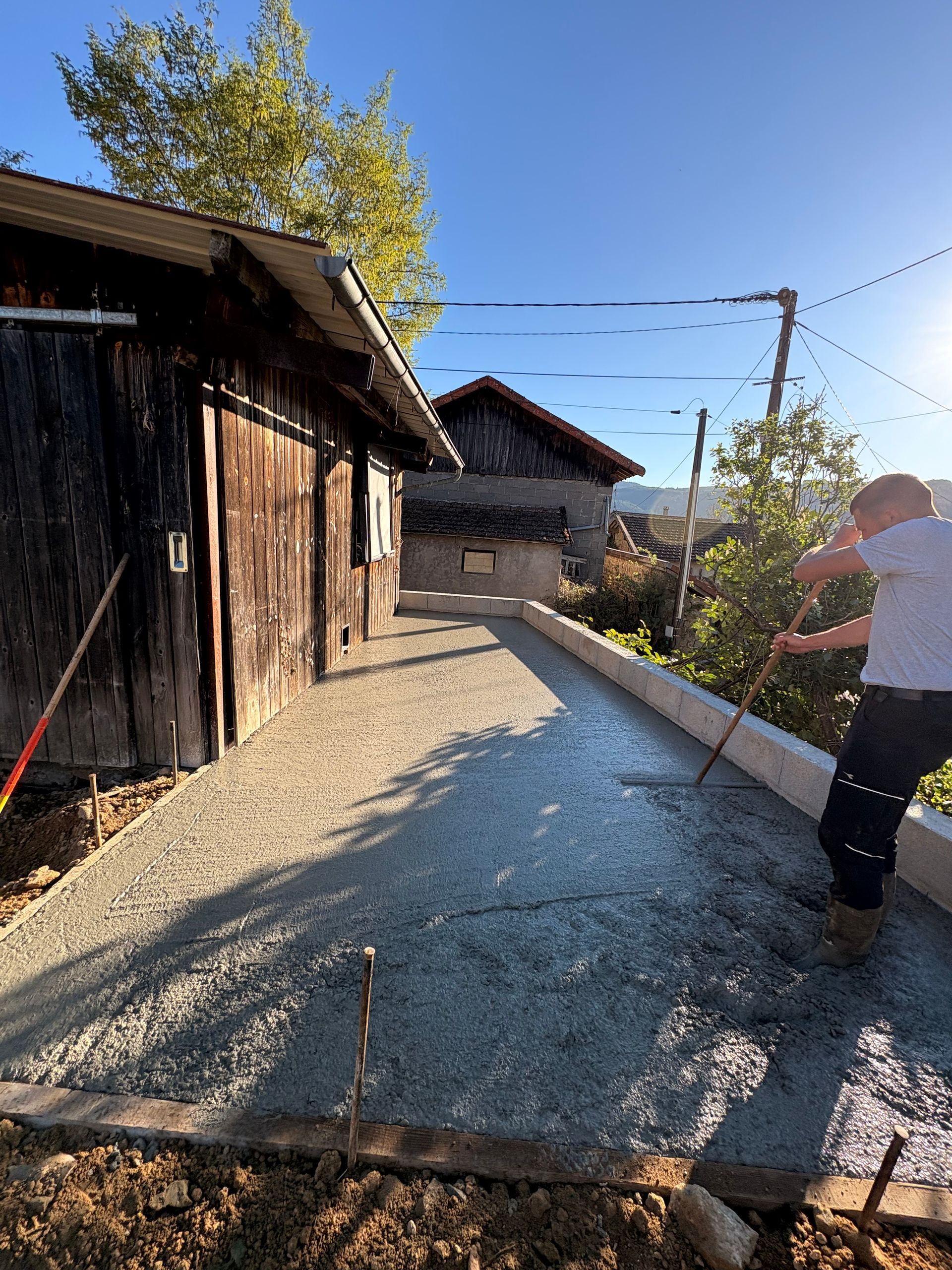 Grande maison avec piliers en pierre et allée sinueuse, encadrée par des arbres dénudés par une journée ensoleillée