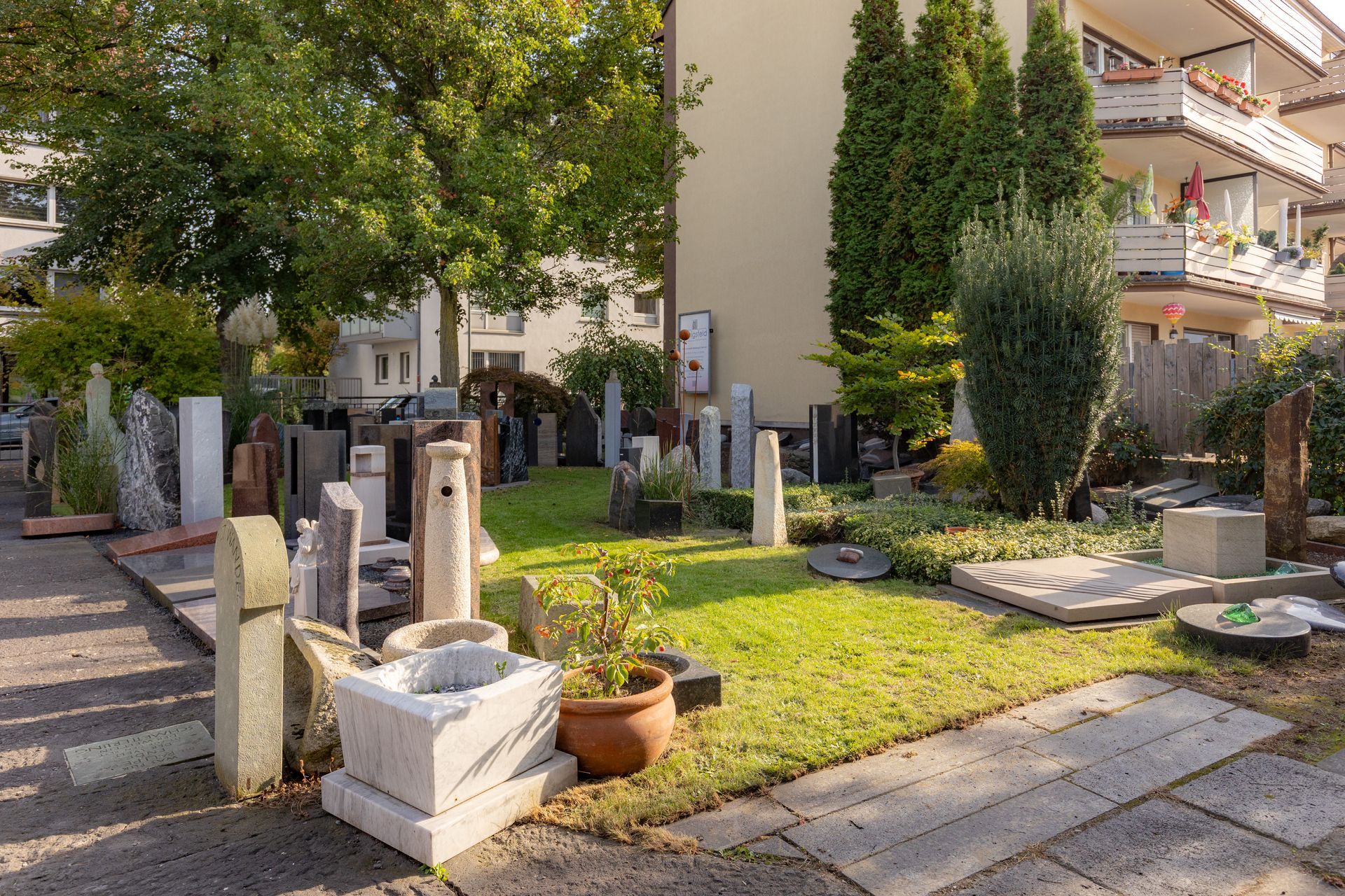 Friedhof mit Grabsteinen und Blumenbeeten in einer grasbewachsenen Umgebung.