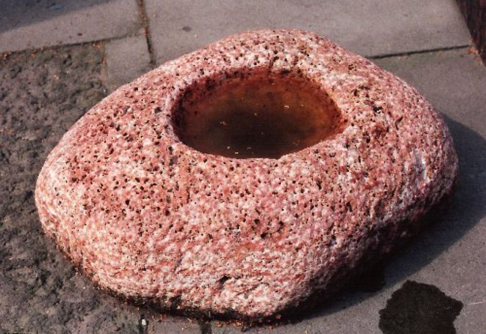 Stein mit eingelassener Schale als Vogeltränke