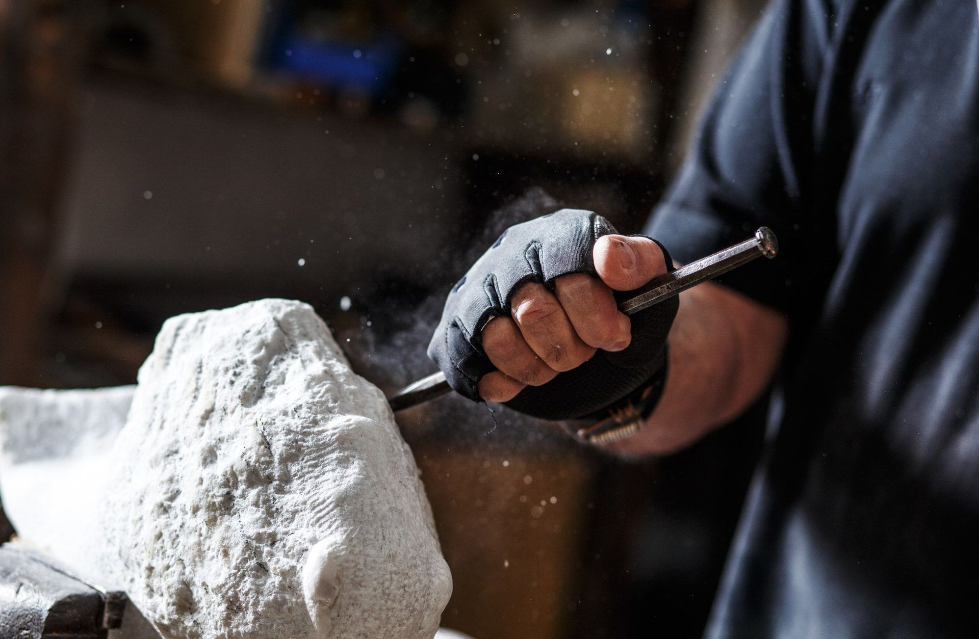 Bildhauer meißelt in einer Werkstatt mit Hammer und Meißel einen Stein.