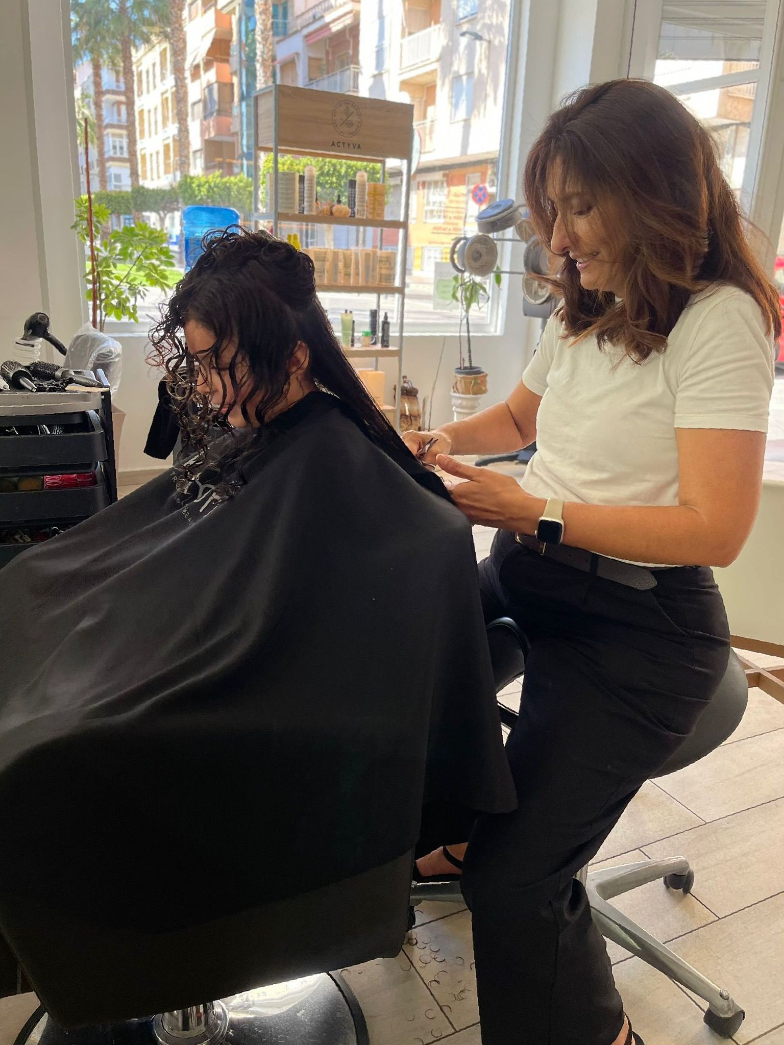 Una mujer está cortando el cabello de otra mujer en un salón.