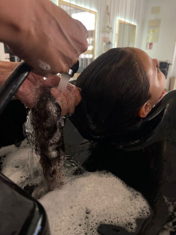 Una mujer se lava el cabello en un lavabo de una peluquería.