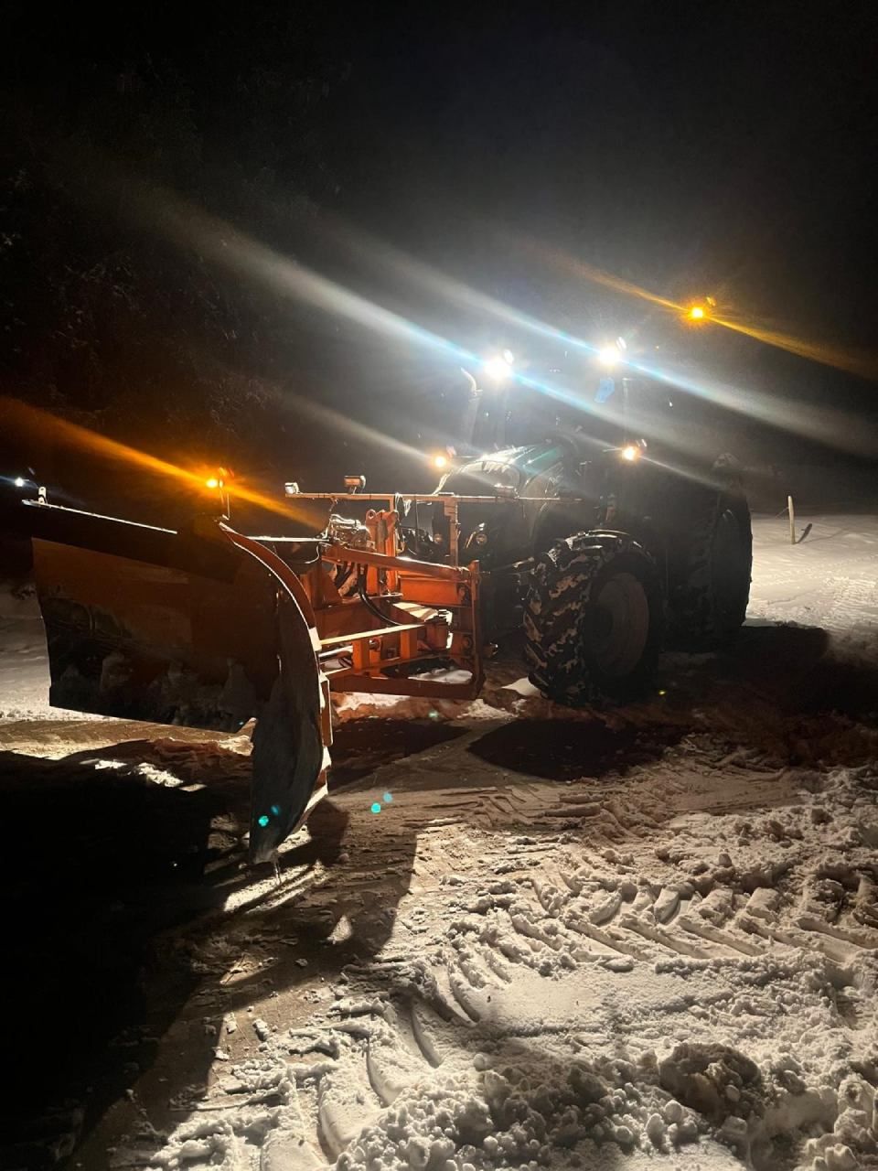 Un chasse-neige roule dans la neige la nuit.