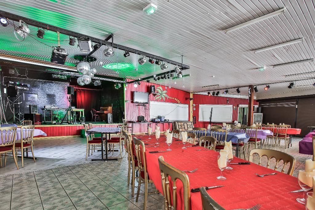 Une salle de banquet avec de longues tables recouvertes de nappes rouges, une scène équipée de projecteurs et un décor festif.