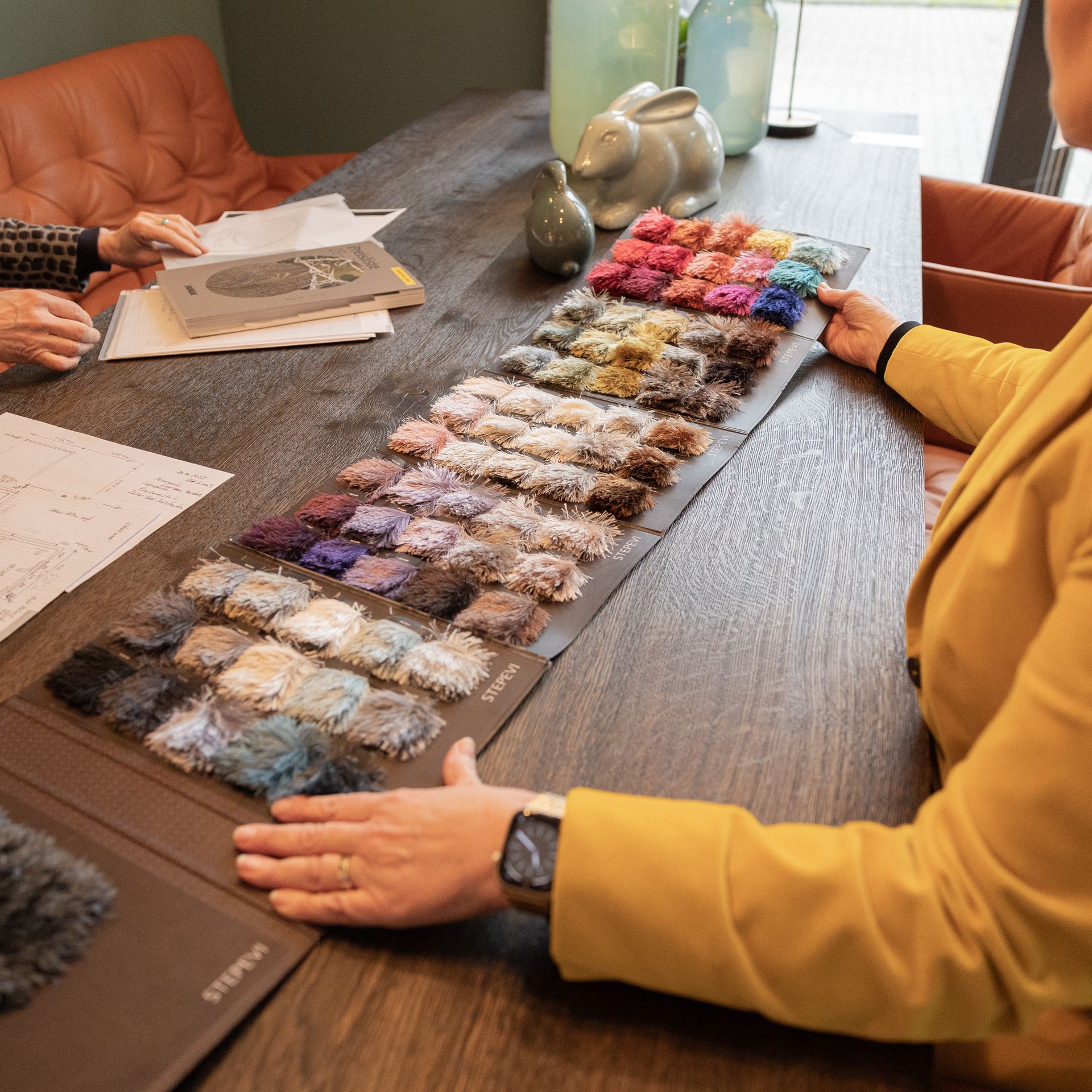 Zwei Frauen sitzen an einem Tisch und schauen sich Stoffmuster an