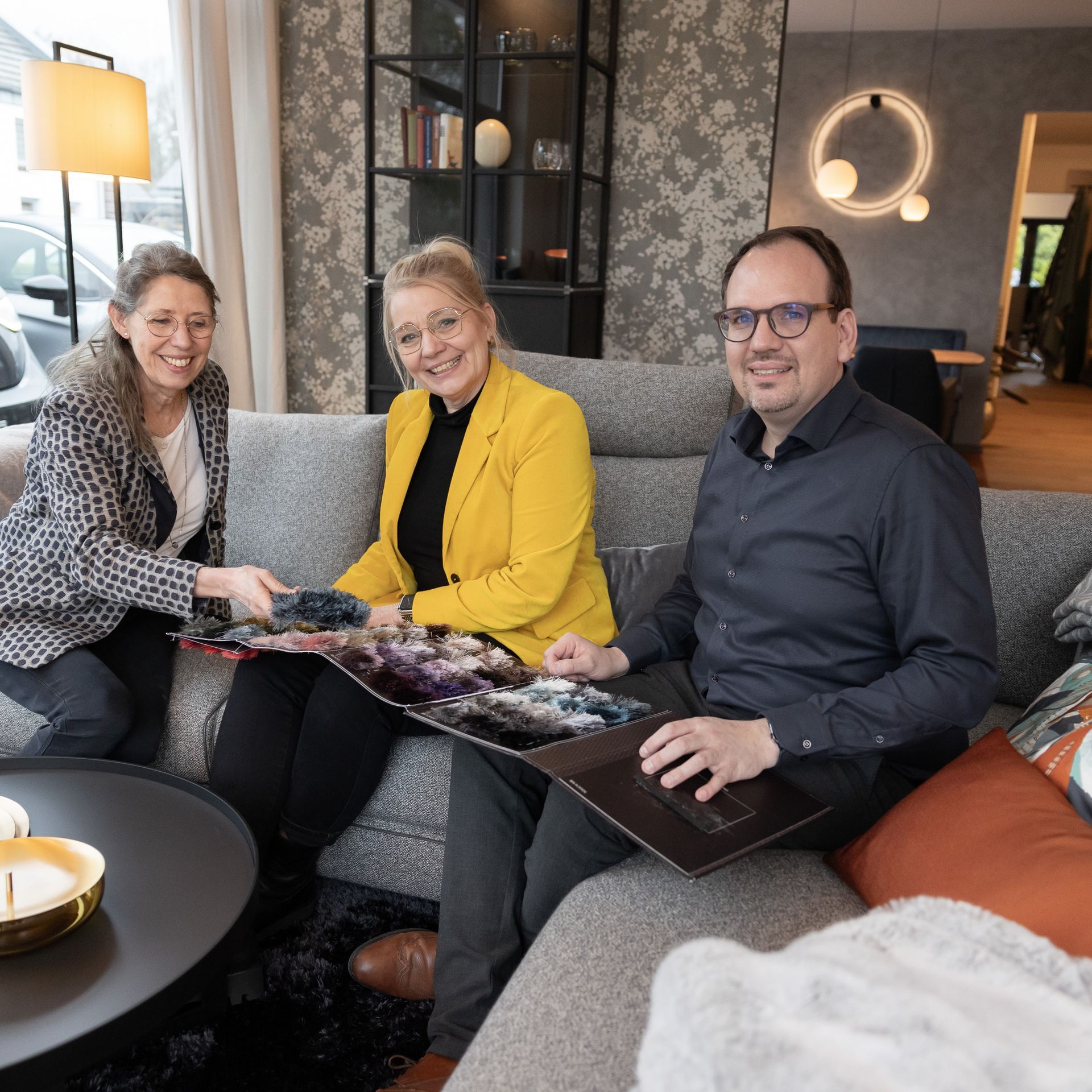 Ein Mann und zwei Frauen sitzen auf einer Couch