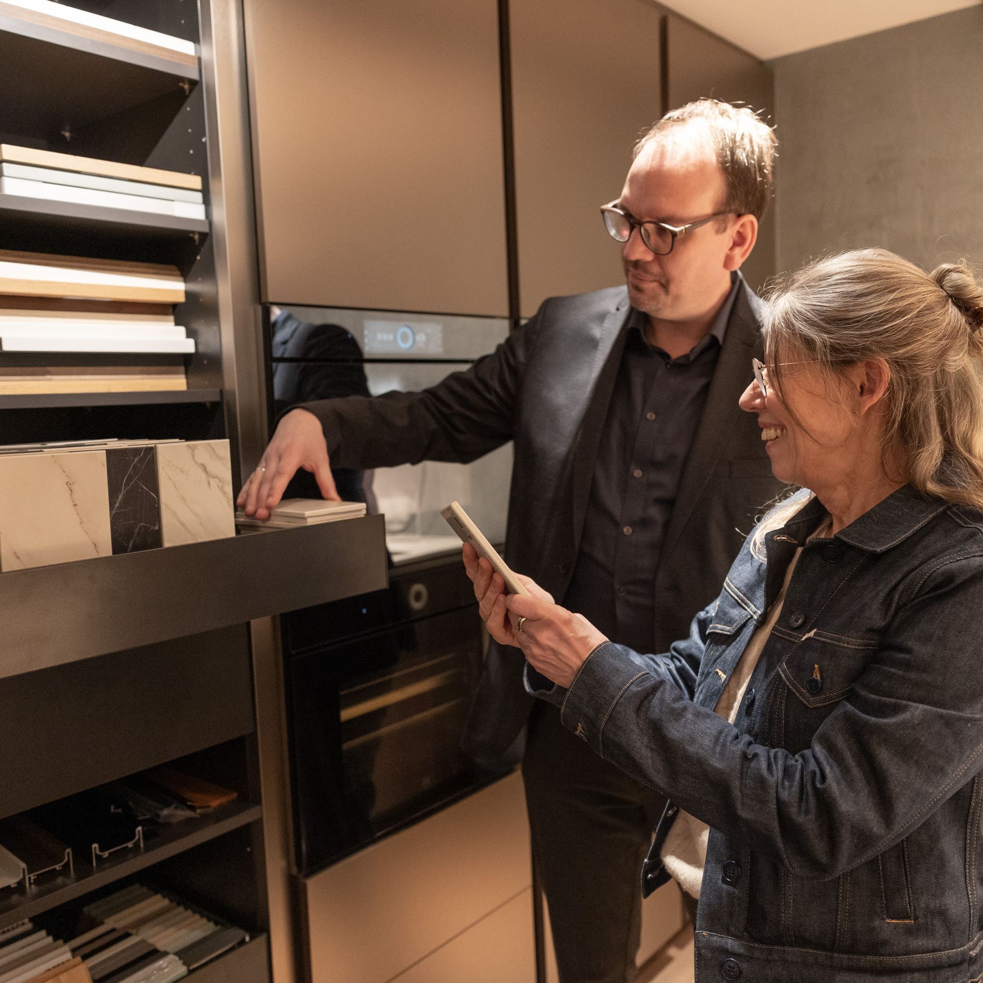 Ein Mann und eine Frau schauen in einer Küche auf ein Telefon