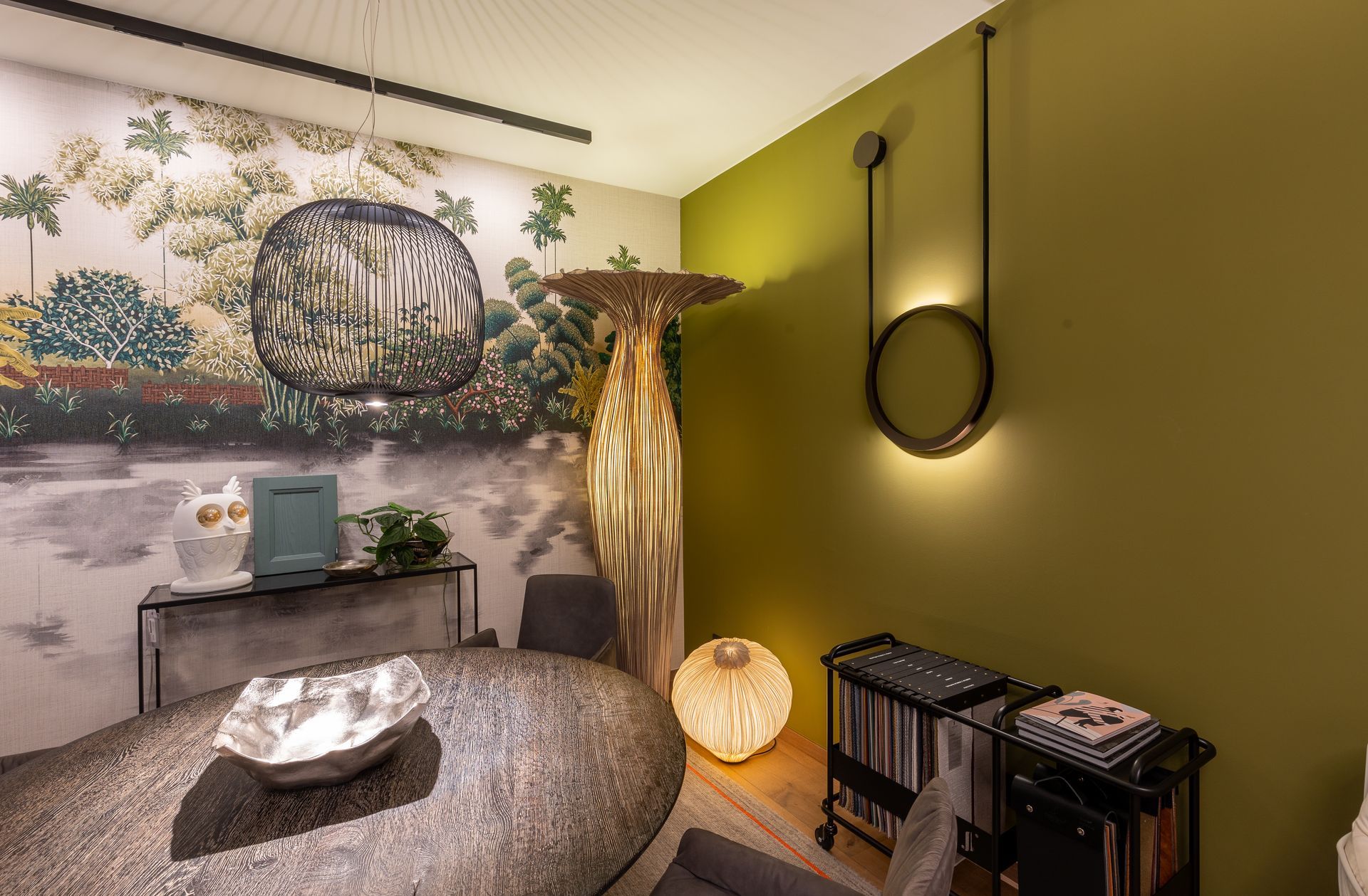 Ein Raum mit einem Tisch, Stühlen, einer Lampe und einem Gemälde an der Wand.