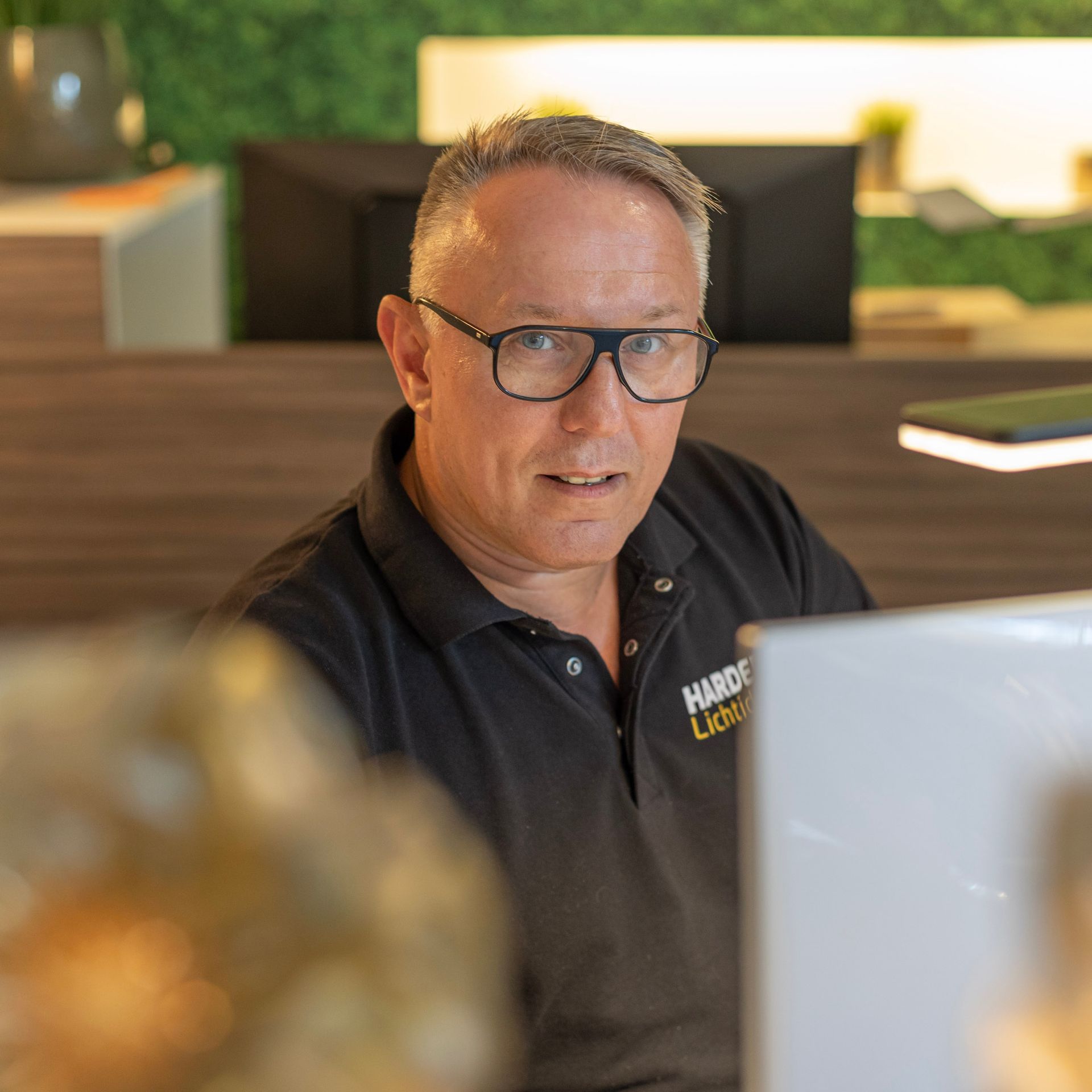 Ein Mann mit Brille sitzt an einem Schreibtisch vor einem Computer.