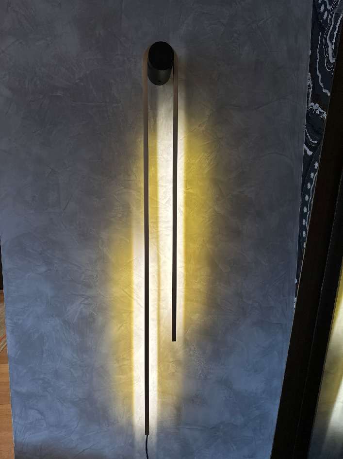 An der Wand neben einer Tür hängt eine lange Lampe.
