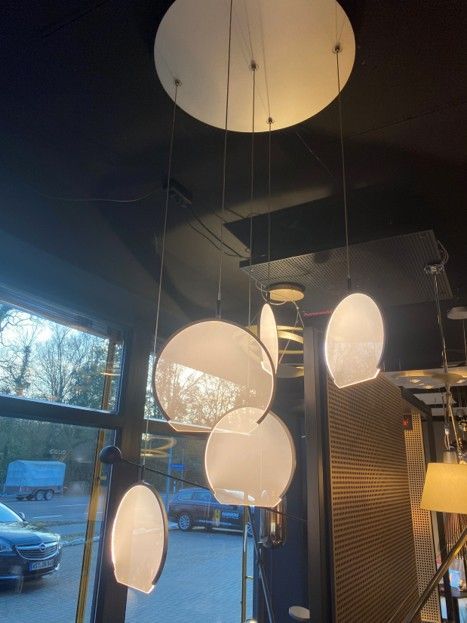 Eine mehrteilige Deckenleuchte mit fünf runden, mattierten Glasscheiben, die in unterschiedlichen Höhen aufgehängt sind.