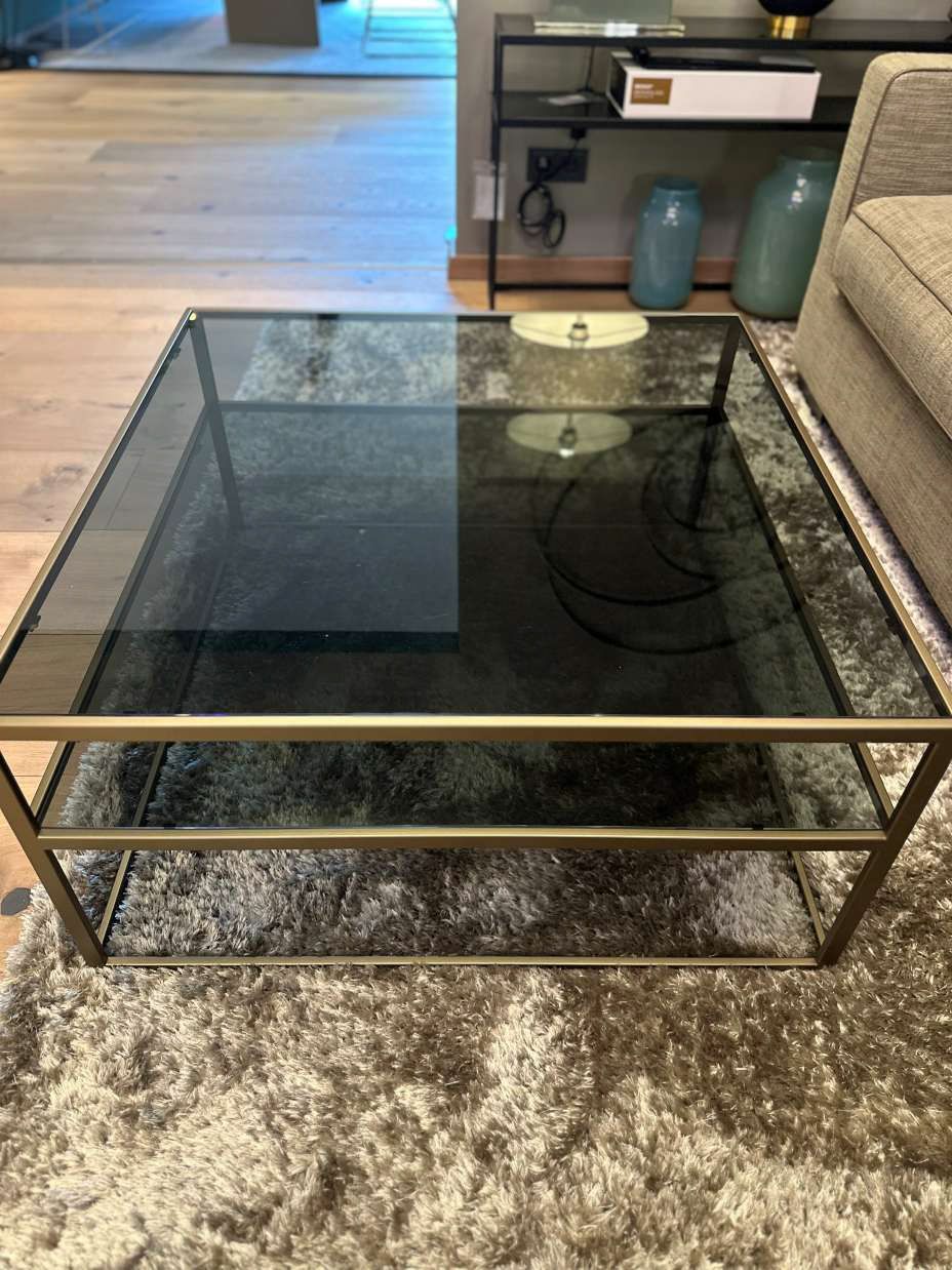 Ein Couchtisch aus Glas steht auf einem Teppich in einem Wohnzimmer.