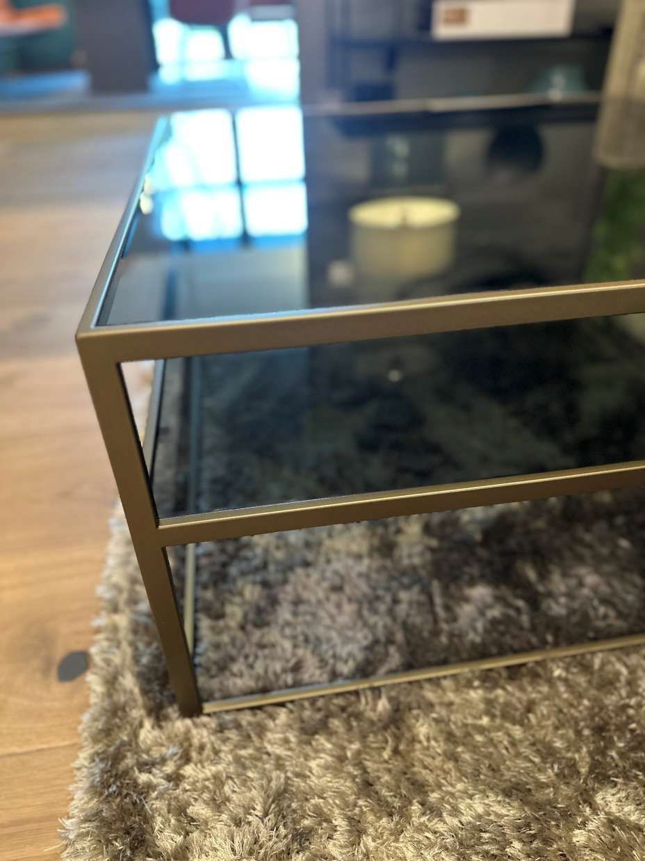 Auf einem Teppich steht ein Couchtisch mit Glasplatte.