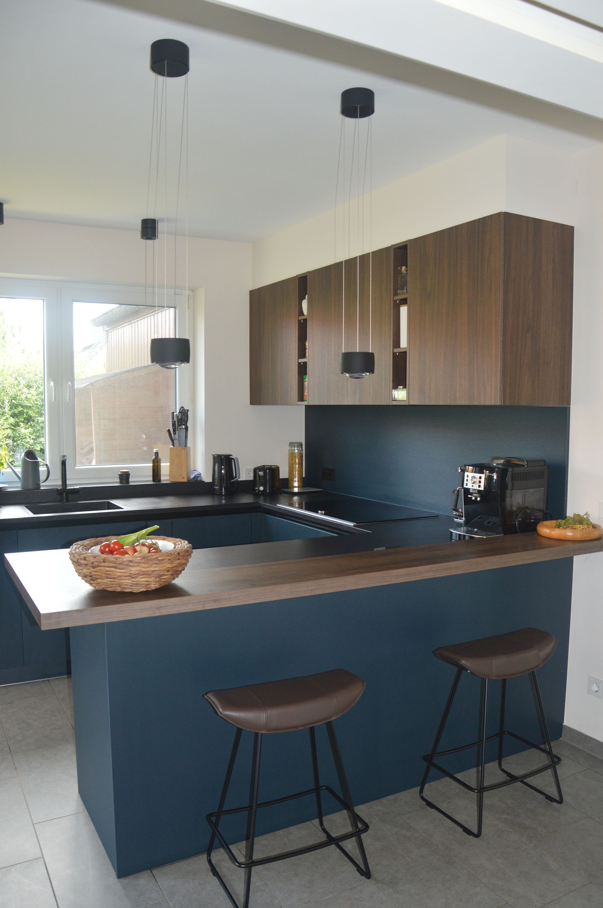 Eine Küche mit einer großen Kochinsel und Hockern und einer Obstschale auf der Theke.