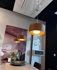 Drei hölzerne Pendelleuchten über einem Esstisch. Die Leuchten sind rund und innen goldfarben.