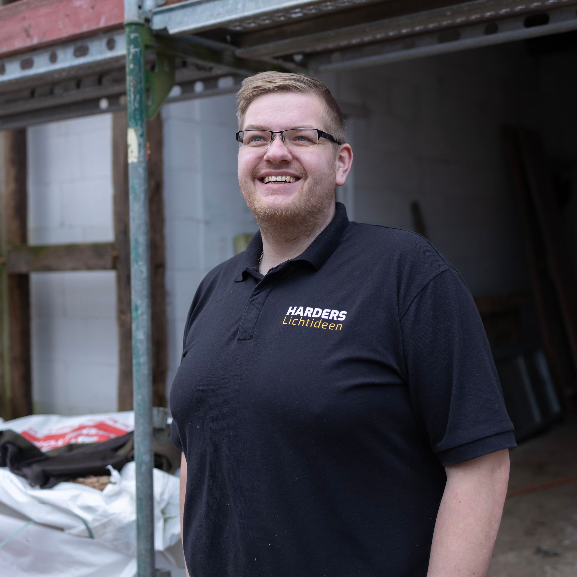 Ein Mann mit Brille und schwarzem Hemd mit der Aufschrift „Harders“ darauf
