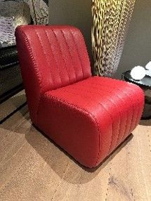 Ein roter Ledersessel steht auf einem Holzboden in einem Wohnzimmer.