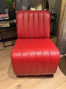 Ein roter Stuhl steht auf einem Holzboden in einem Wohnzimmer.