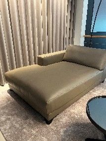 Eine Chaiselongue steht in einem Wohnzimmer neben einem Tisch.