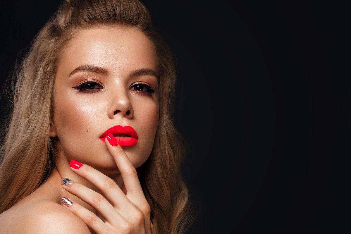 La mujer lleva lápiz labial rojo y uñas rojas.