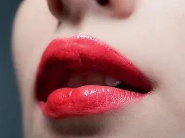 Un primer plano de los labios de una mujer con lápiz labial rojo.