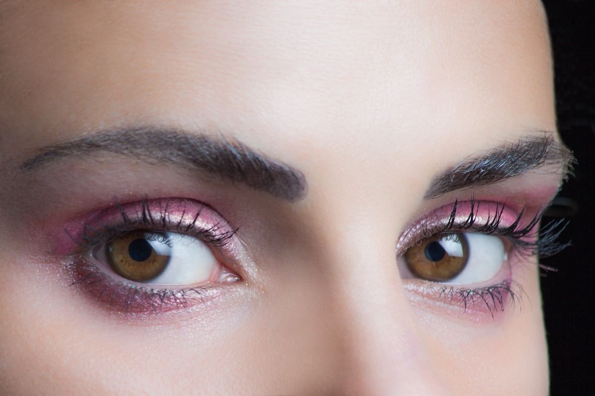 Un primer plano de los ojos de una mujer con sombra de ojos rosa.