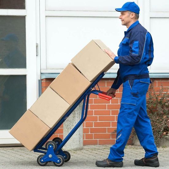 Un hombre empuja un carrito lleno de cajas de cartón.