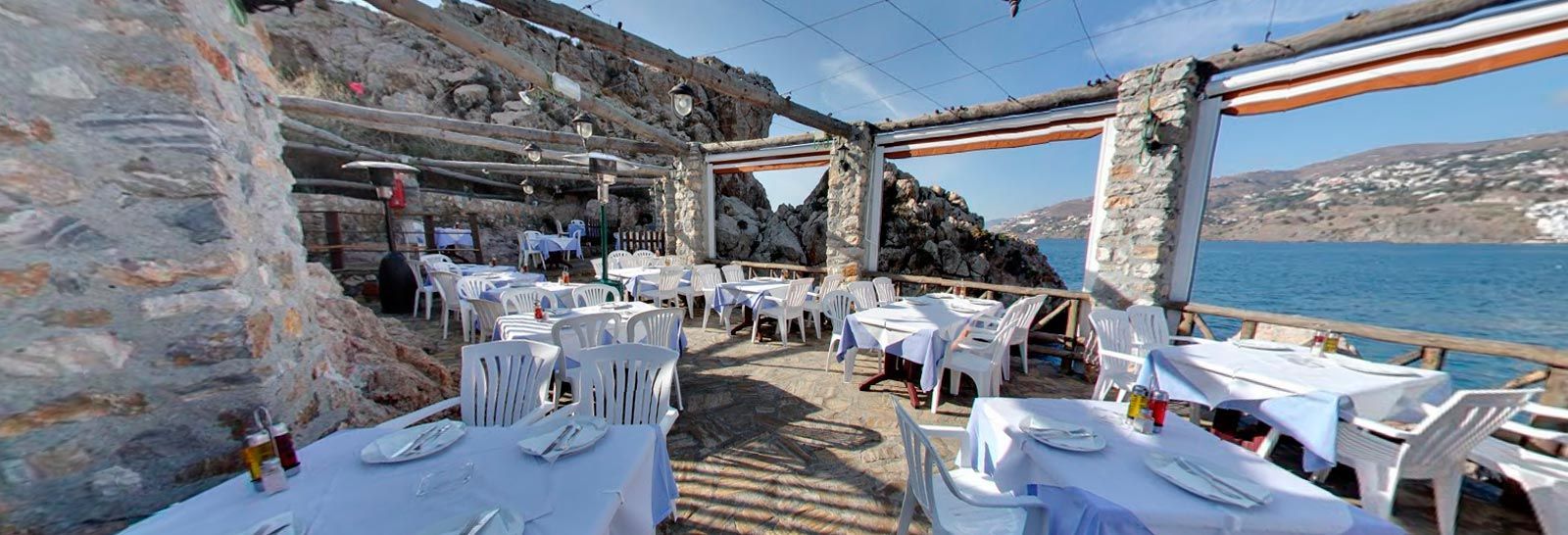 Un restaurante con mesas y sillas con vista al mar.