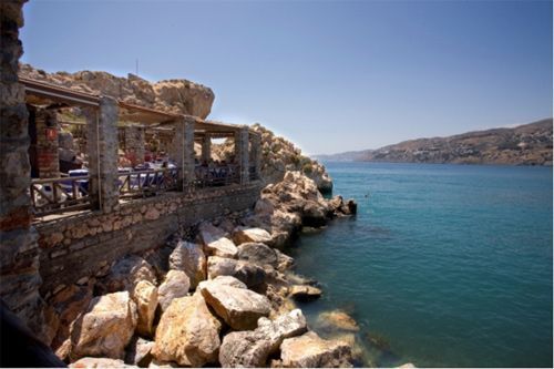 Un acantilado con vistas a un cuerpo de agua con un restaurante al fondo.
