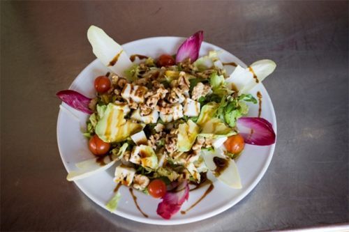 Un primer plano de una ensalada en un plato sobre una mesa.