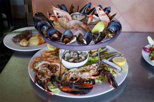 Un plato de mariscos está sobre una mesa con otros platos de comida.