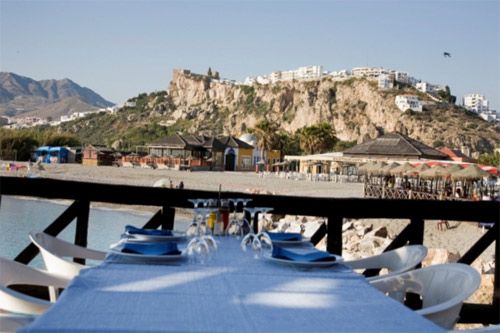 Una mesa con platos y vasos con una montaña al fondo.