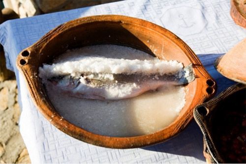Un pez en un recipiente con sal sobre una mesa.
